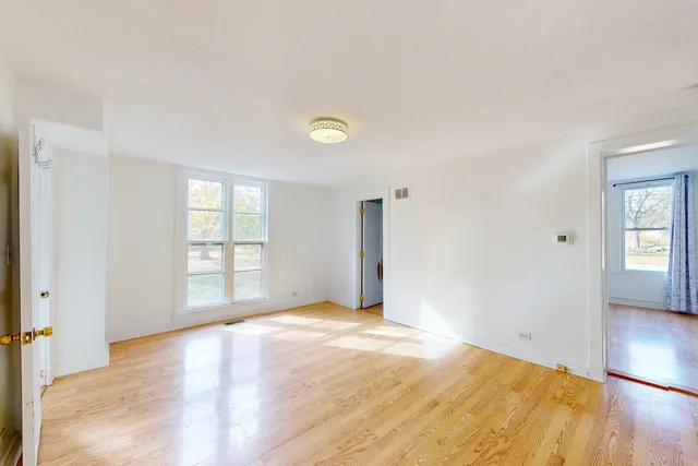 a view of a bedroom with wooden floor and window