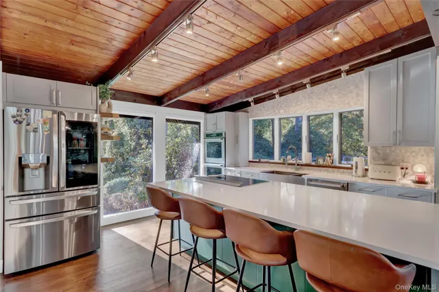 a dining room with stainless steel appliances granite countertop a table chairs and wooden floor