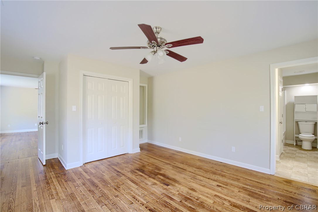 5347 Ware Neck Road Gloucester, VA 23061 - Photo 16 of 36 Unfurnished bedroom featuring connected bathroom, a closet, ceiling fan, and light wood-type flooring