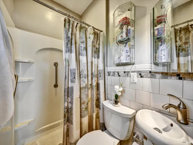 a bathroom with a sink a mirror a toilet and shower