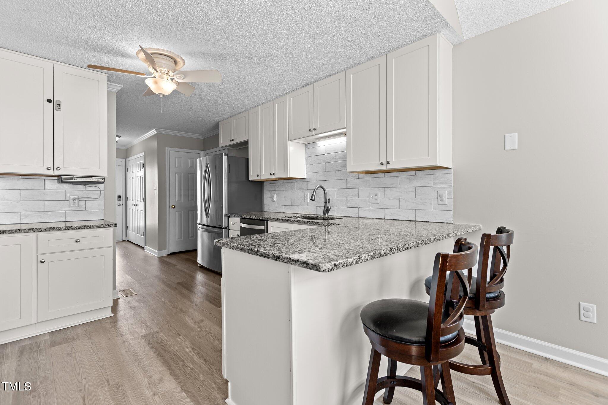 1408 Harvey Johnson Road Raleigh, NC 27603 - Photo 14 of 48 a kitchen with granite countertop white cabinets and stainless steel appliances