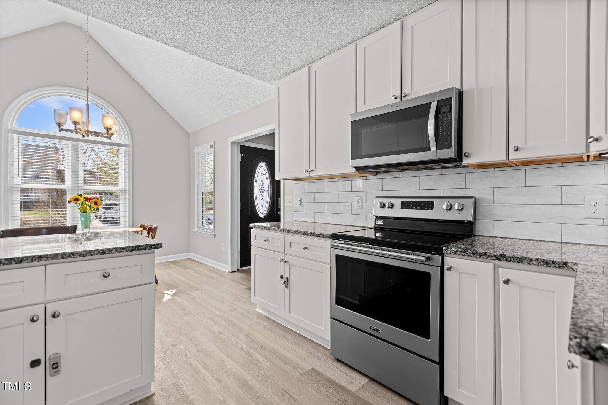 1408 Harvey Johnson Road Raleigh, NC 27603 - Photo 16 of 48 a kitchen with stainless steel appliances granite countertop a stove a microwave and a white cabinets