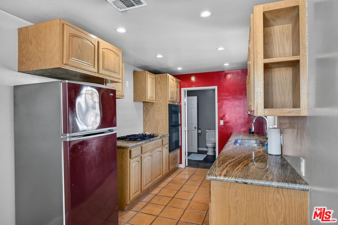 3692 Buckingham Road Los Angeles, CA 90016 - Photo 19 of 40 a kitchen with granite countertop stainless steel appliances a refrigerator a sink and cabinets