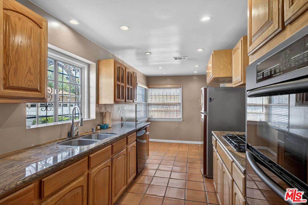 3692 Buckingham Road Los Angeles, CA 90016 - Photo 22 of 40 a kitchen with stainless steel appliances a sink stove and cabinets