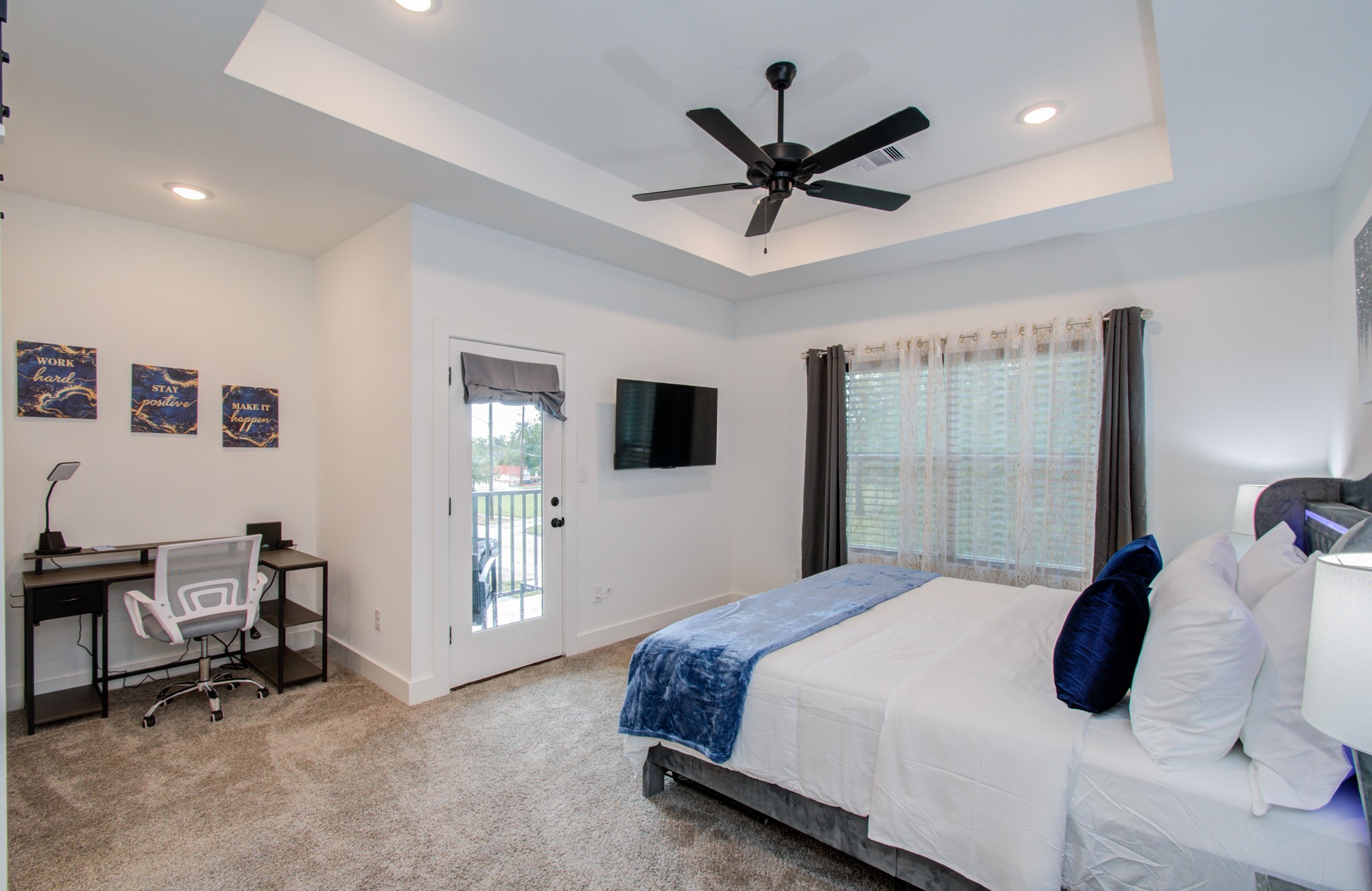 1616 Benson Street Houston, TX 77020 - Photo 19 of 38 a bedroom with a large bed a flat tv screen and a ceiling fan