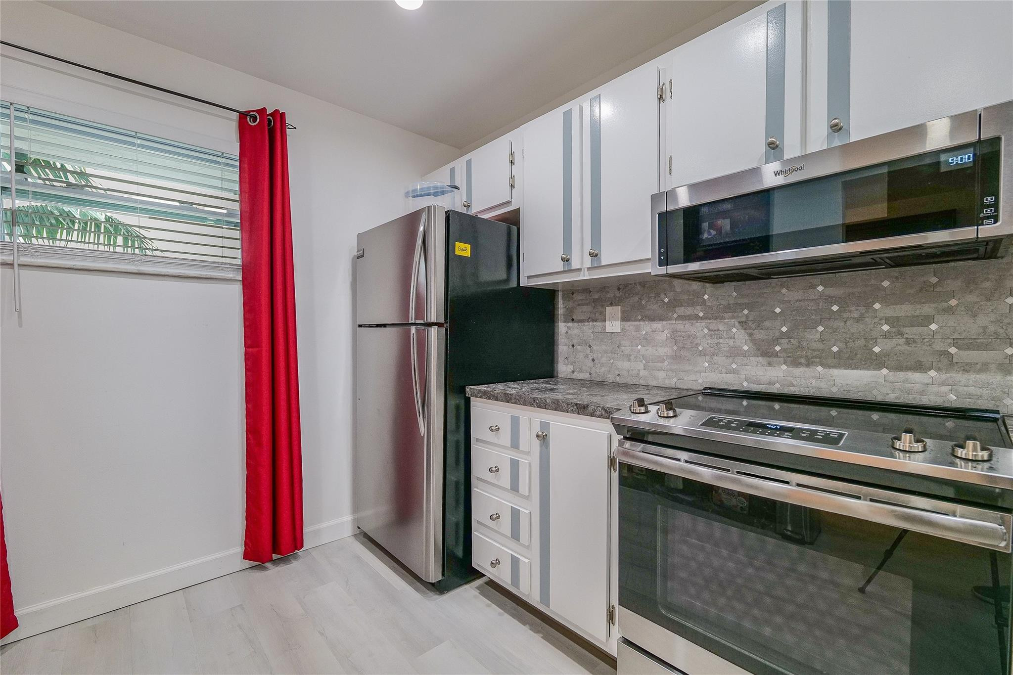 3930 Inverrary Boulevard, Unit 407D Lauderhill, FL 33319 - Photo 10 of 60 a kitchen with stainless steel appliances a stove a microwave and a refrigerator