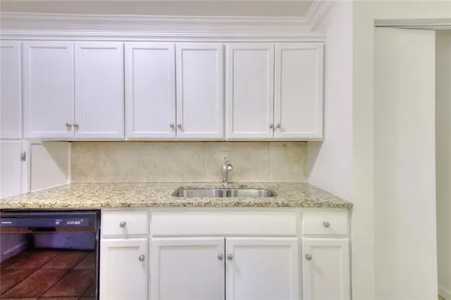 a kitchen with granite countertop white cabinets and a sink
