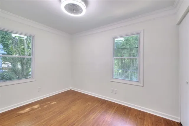 an empty room with wooden floor and windows