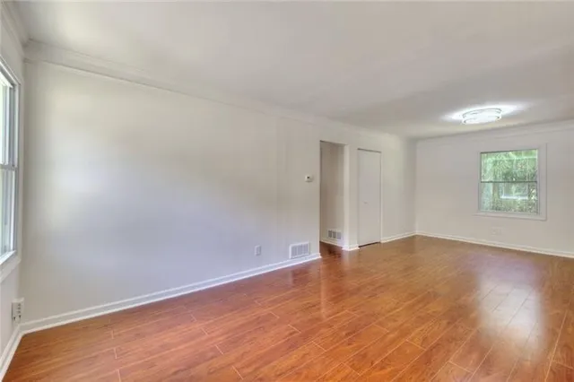 an empty room with wooden floor and windows