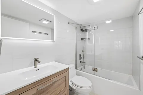 a bathroom with a bathtub shower sink mirror vanity and toilet