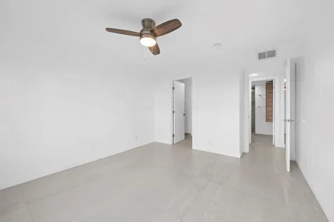an empty room with ceiling fan and window
