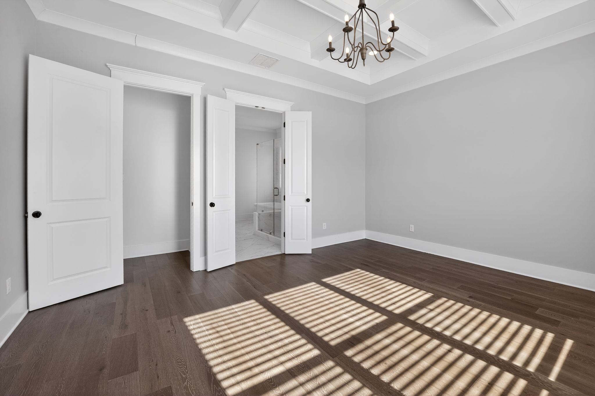 1421 Peyton Run Loop South Collierville, TN 38017 - Photo 16 of 29 Unfurnished bedroom with ornamental molding, coffered ceiling, beam ceiling, a chandelier, and dark wood-type flooring