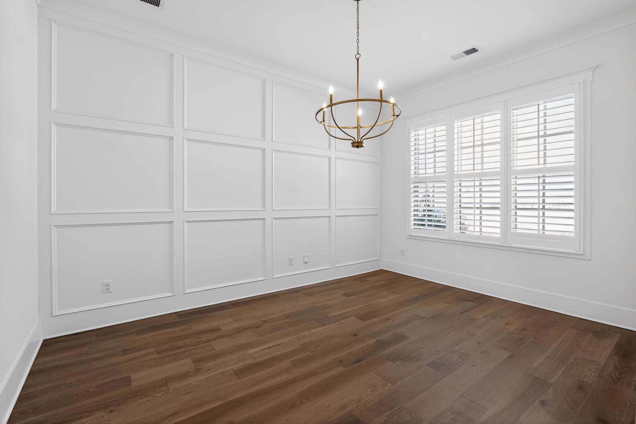 1421 Peyton Run Loop South Collierville, TN 38017 - Photo 9 of 29 Unfurnished dining area featuring a decorative wall, a chandelier, and dark wood-style floors
