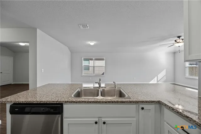 a kitchen with granite countertop a sink and cabinets