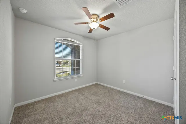 an empty room with ceiling fan and windows