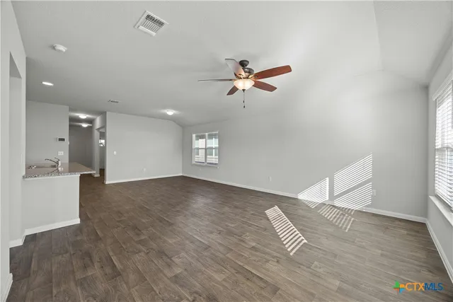 a view of an empty room with a window and wooden floor