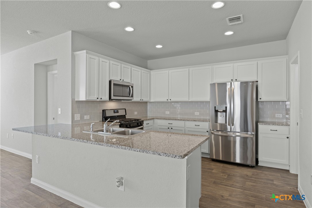 118 Rochester Lane Hutto, TX 78634 - Photo 9 of 33 a kitchen with a refrigerator a microwave a sink and cabinets