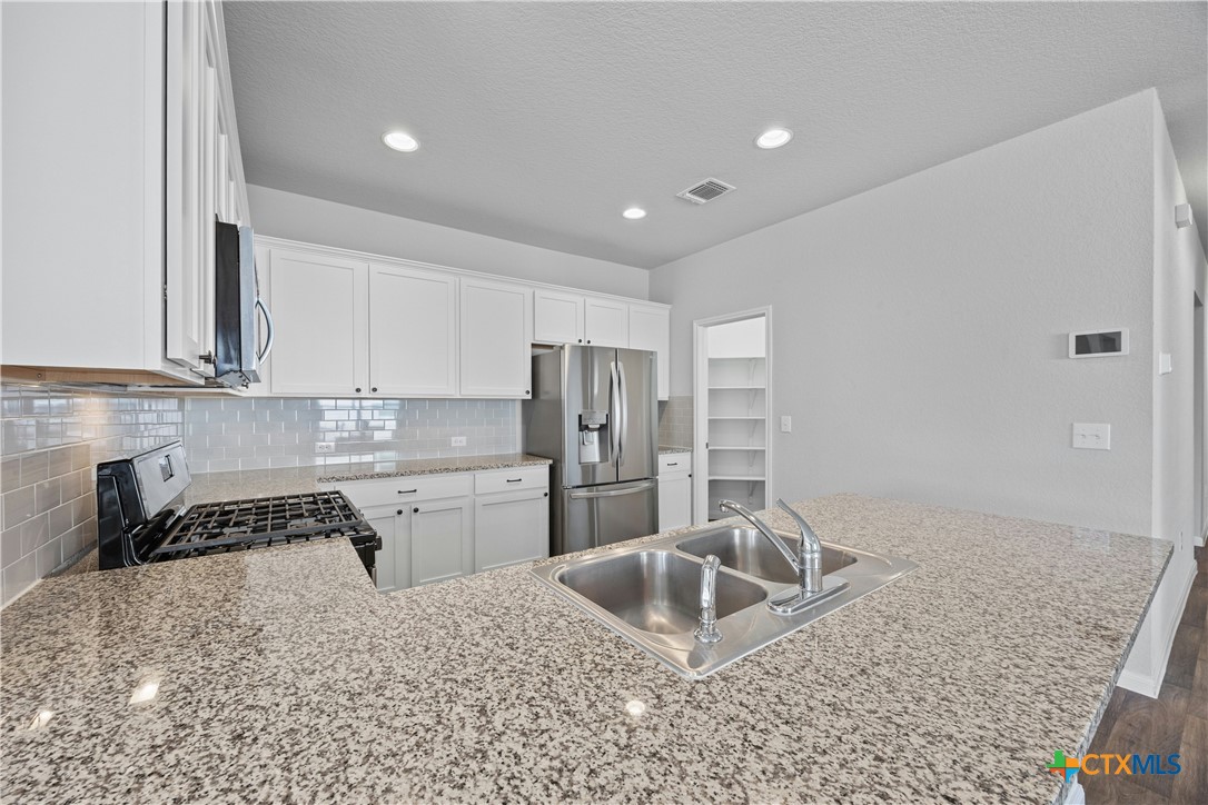 118 Rochester Lane Hutto, TX 78634 - Photo 10 of 33 a kitchen with stainless steel appliances granite countertop a sink stove and refrigerator