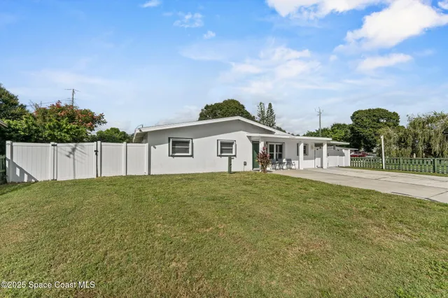 a view of a yard in front of a house with a large tree