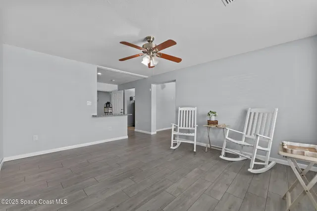 a view of a livingroom with wooden floor and a ceiling fan