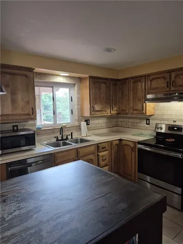a kitchen with kitchen island sink stove and refrigerator