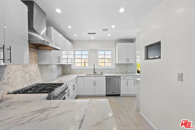 a large kitchen with stainless steel appliances granite countertop a stove a sink and a refrigerator