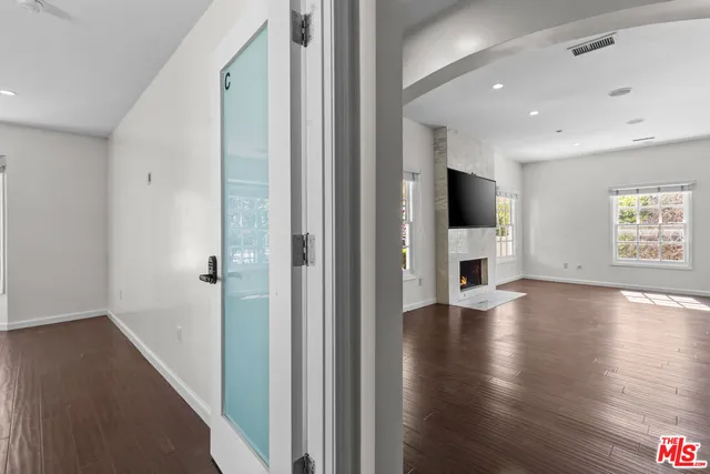 a view of a hallway with wooden floor and a bathroom