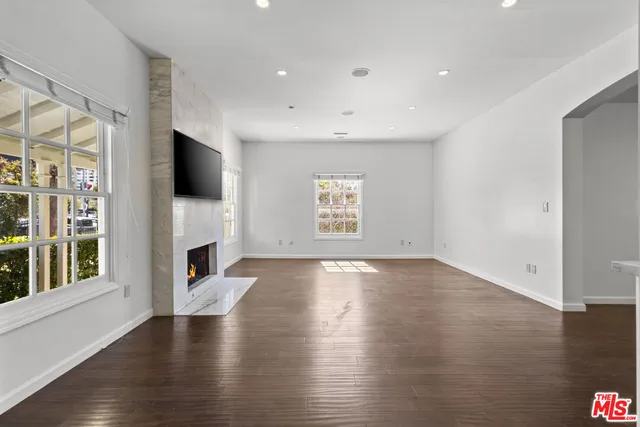 an empty room with wooden floor fireplace and windows