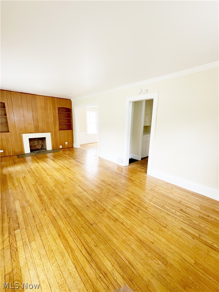 3345 Sylvanhurst Road Cleveland Heights, OH 44112 - Photo 6 of 16 Unfurnished living room with ornamental molding, light hardwood / wood-style flooring, and wooden walls