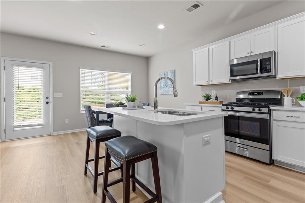325 Winston Circle Canton, GA 30114 - Photo 12 of 38 a kitchen with stainless steel appliances a white table and chairs in it