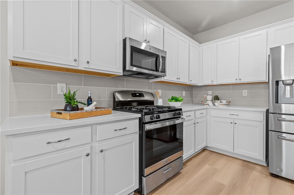 325 Winston Circle Canton, GA 30114 - Photo 16 of 38 a kitchen with stainless steel appliances granite countertop white cabinets a sink a stove a refrigerator and microwave with wooden floor