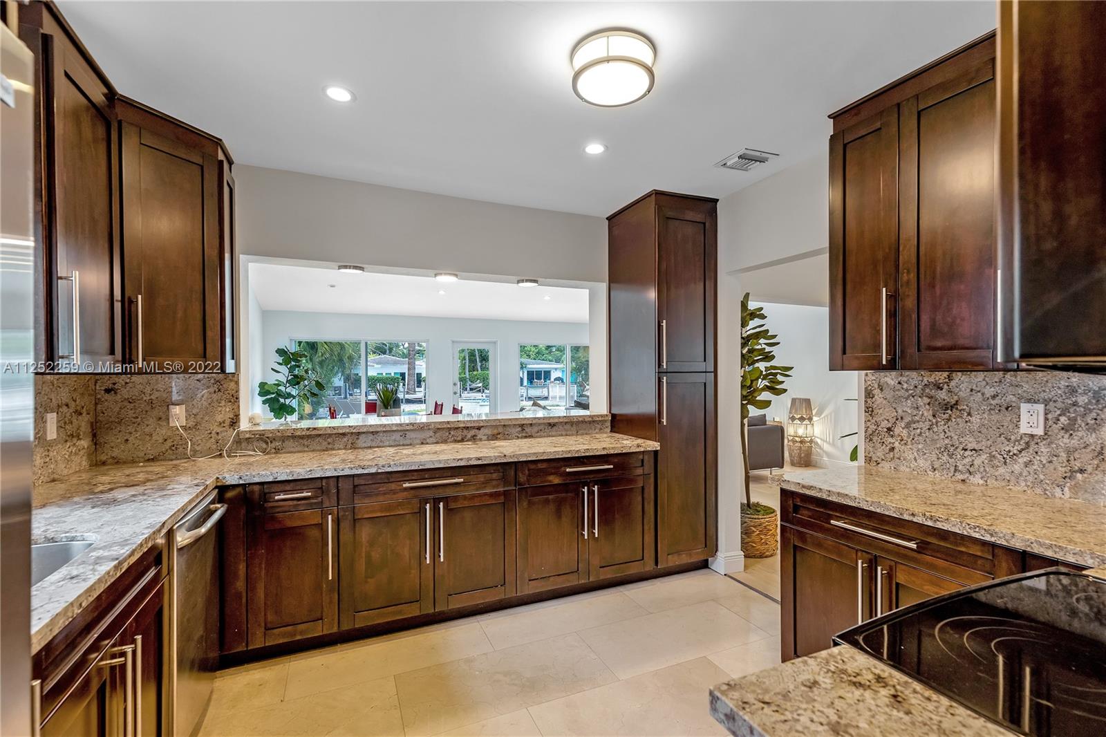 1757 Daytonia Road Miami Beach, FL 33141 - Photo 16 of 30 a kitchen with stainless steel appliances granite countertop wooden cabinets a sink and a stove