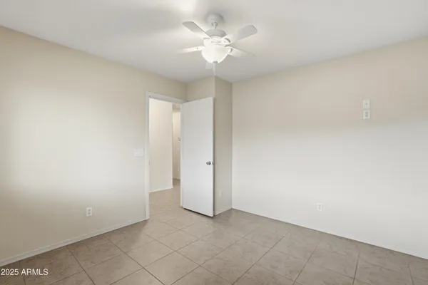 an empty room with a chandelier fan and windows