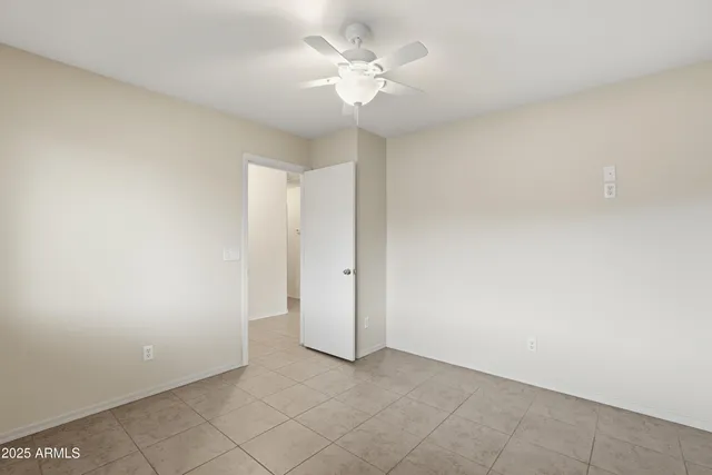 an empty room with a chandelier fan and windows