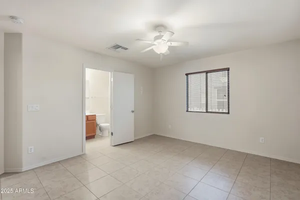 an empty room with a chandelier fan and windows