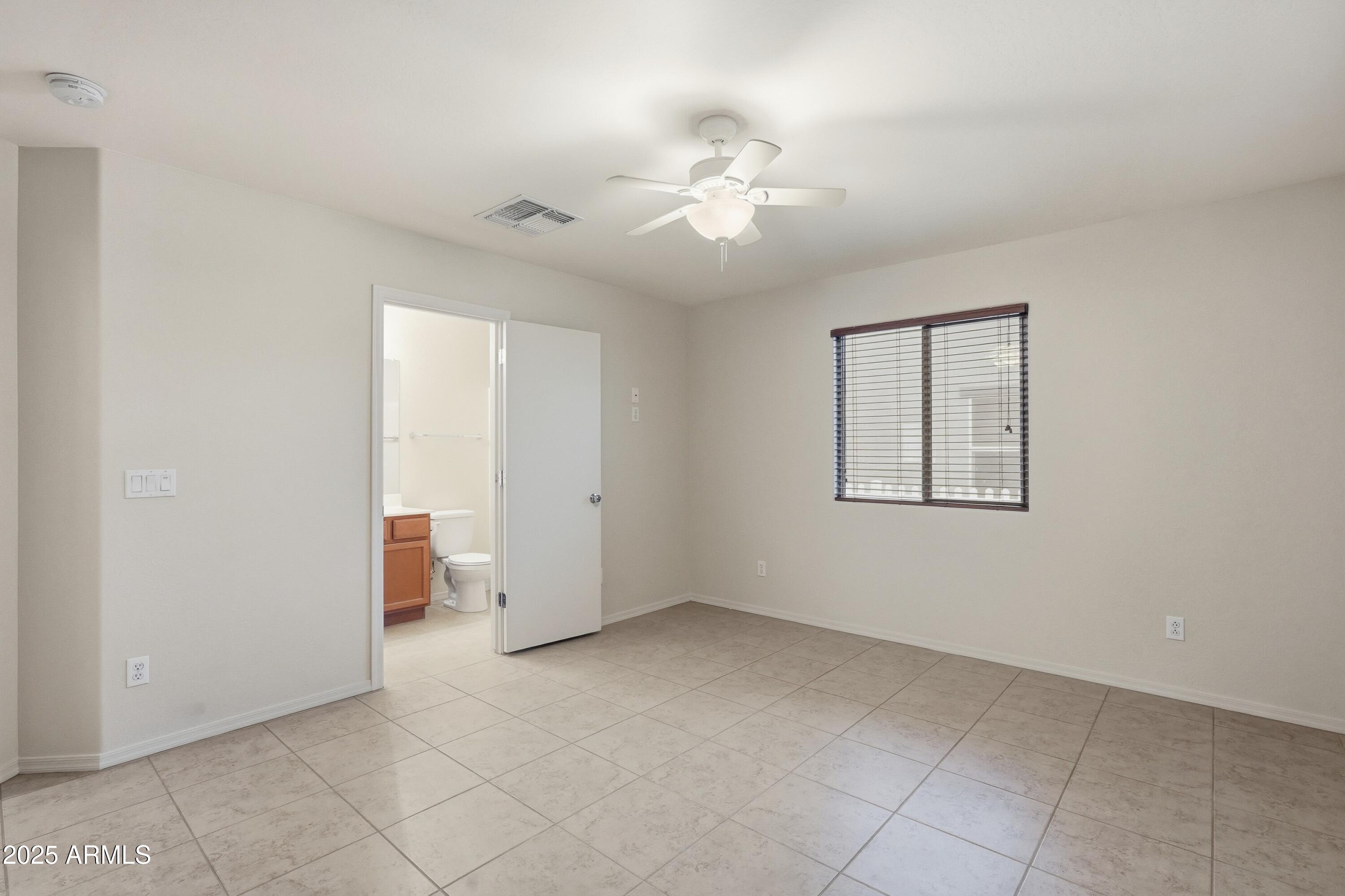 2101 South Meridian Road, Unit 210 Apache Junction, AZ 85120 - Photo 21 of 32 an empty room with a chandelier fan and windows