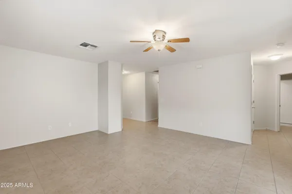 an empty room with chandelier fan and windows