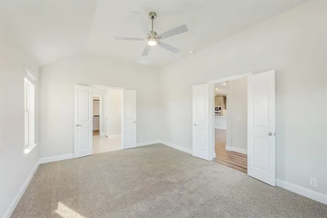 a view of a livingroom with a ceiling fan & windows