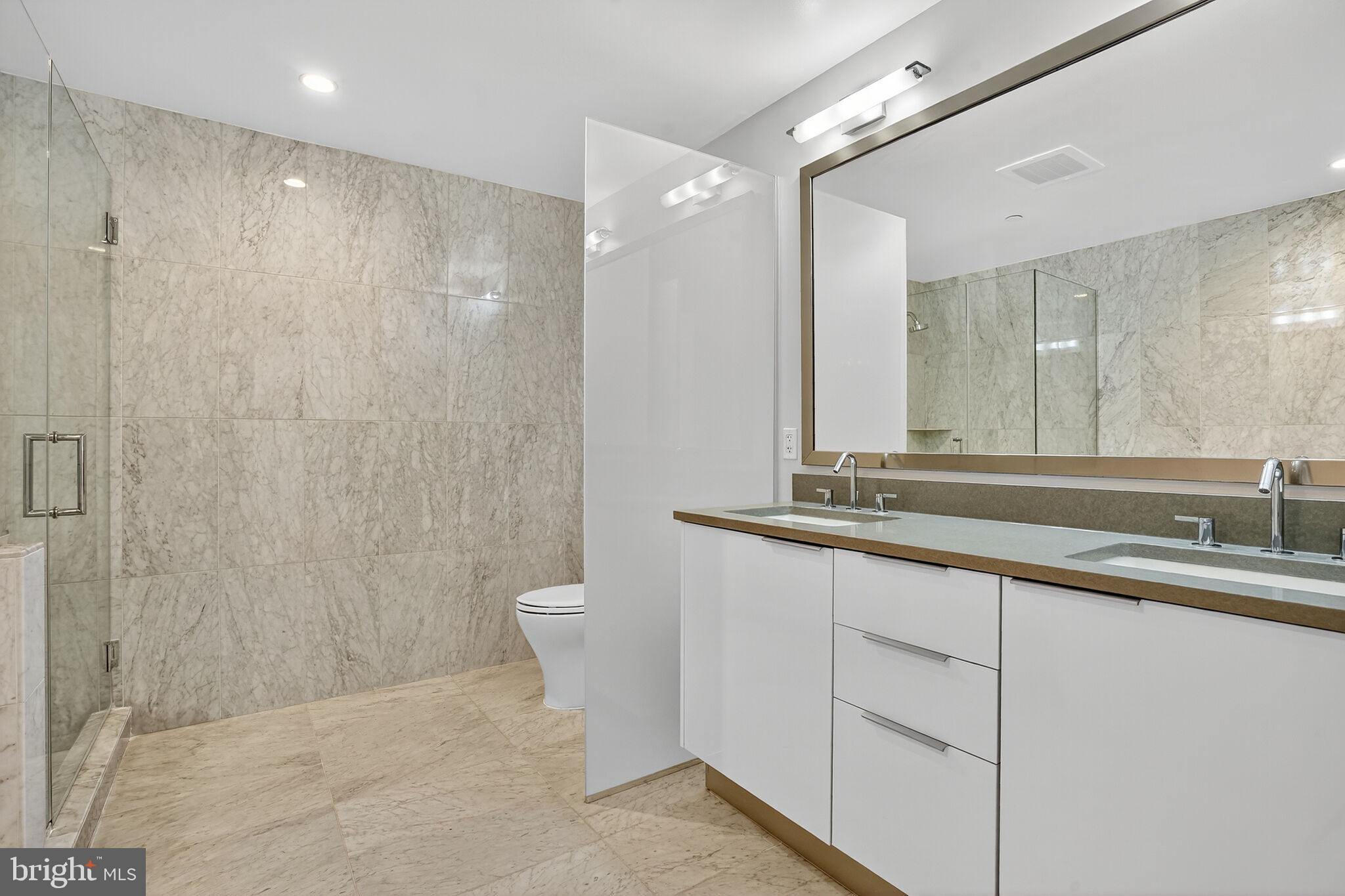 45 Sutton Square Southwest, Unit 509 Washington, DC 20024 - Photo 13 of 25 a bathroom with a double vanity sink a toilet and a mirror