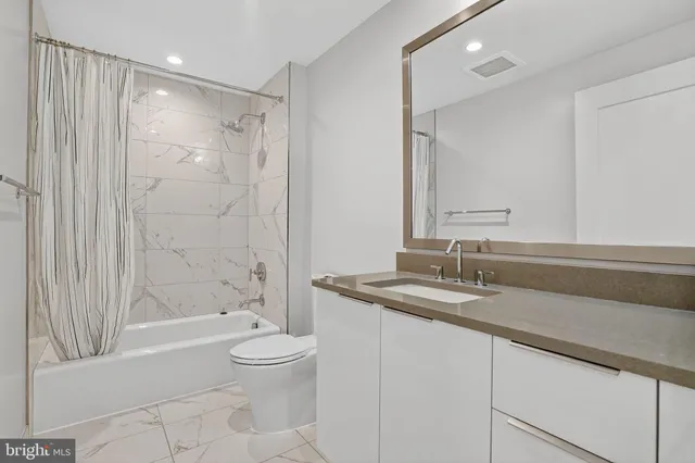 a bathroom with a granite countertop sink a toilet and shower