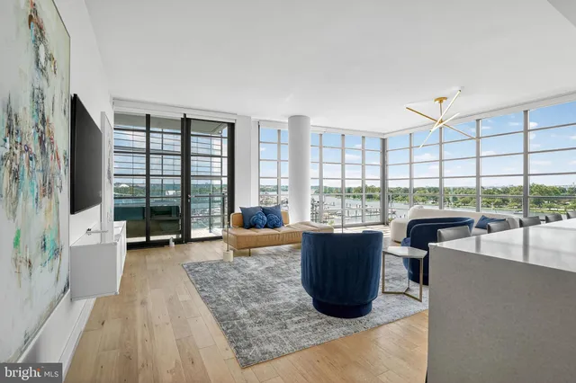 a living room with furniture large windows and wooden floor