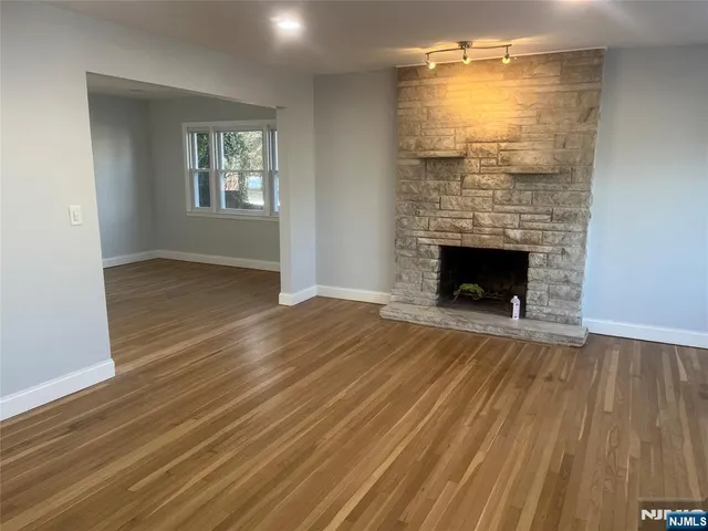 an empty room with wooden floor fireplace and windows