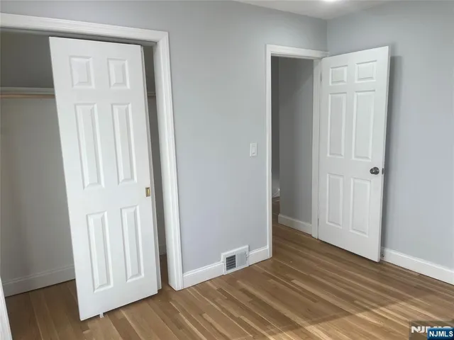 an empty room with wooden floor & closet area