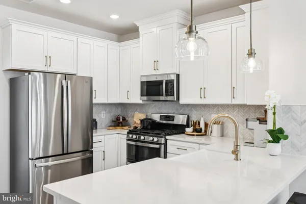 a kitchen with refrigerator a microwave a sink and white cabinets