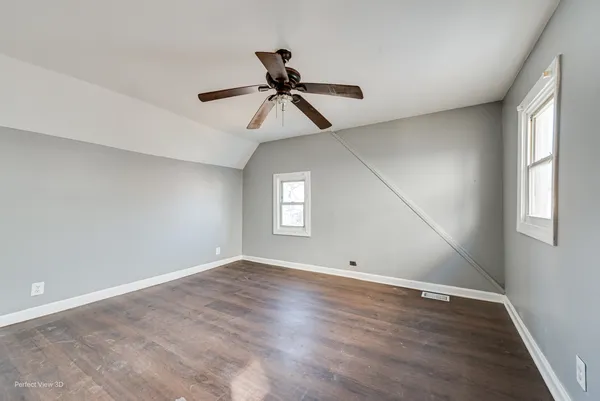 an empty room with wooden floor ceiling fan and windows