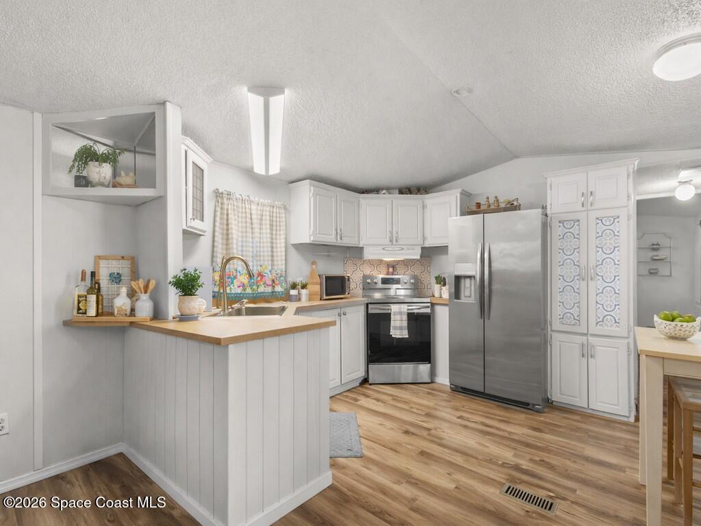 7380 129th Place Sebastian, FL 32958 - Photo 17 of 32 a kitchen with stainless steel appliances a refrigerator a sink dishwasher a stove and white cabinets with wooden floor