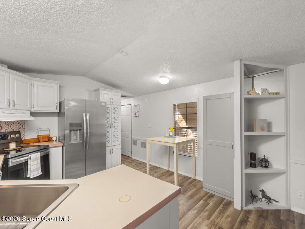 7380 129th Place Sebastian, FL 32958 - Photo 21 of 32 a kitchen with stainless steel appliances kitchen island granite countertop a refrigerator a sink a stove and white cabinets with wooden floor