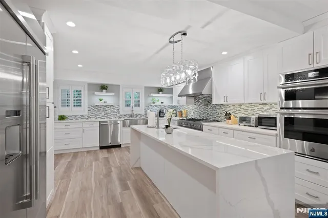 a large white kitchen with lots of counter space a sink appliances and cabinets