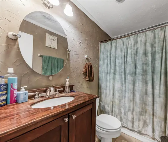 a bathroom with a granite countertop sink vanity mirror and toilet