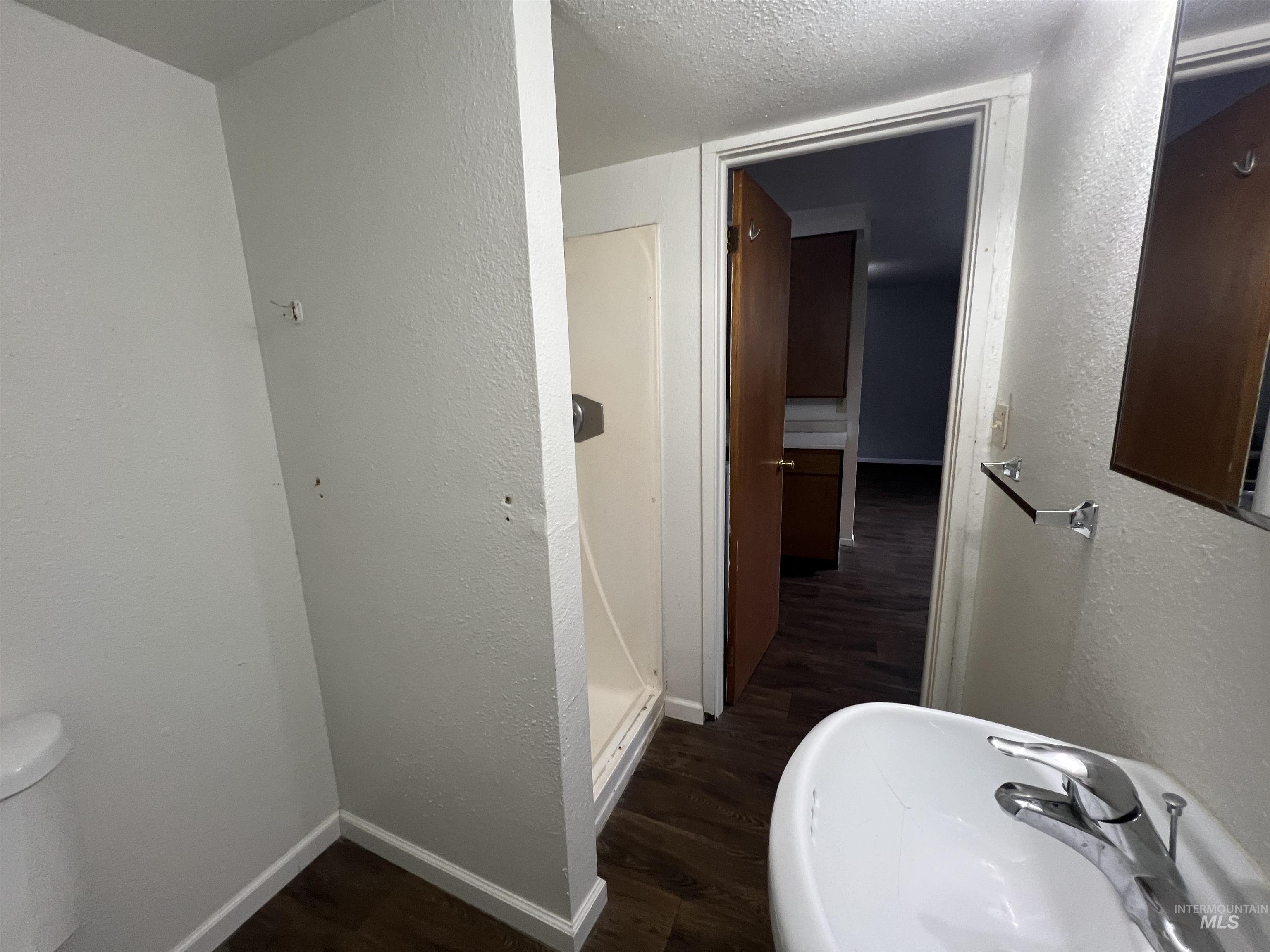 151 Northwest 8th Street Ontario, OR 97914 - Photo 17 of 30 Bathroom with a textured wall, dark wood-type flooring, a textured ceiling, and a shower stall